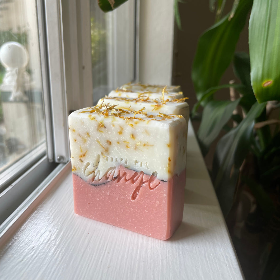 rose and natural colored layered soap with a dark line separating the layers and topped with calendula petals